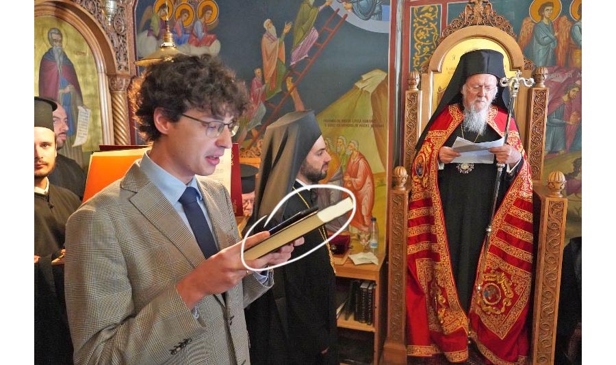 A reader serves with Patriarch Bartholomew, reading prokimena from a gadget (October 2023)