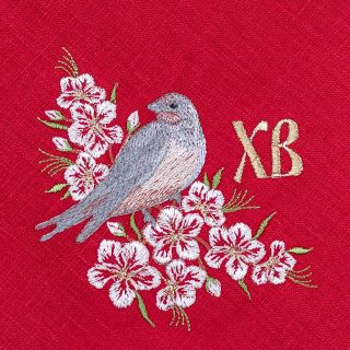 paschal red linen kitchen napkin with embroidered birds and cherry tree in blossom
