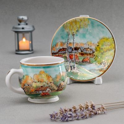 handmade ceramic coffee cup and saucer with a church in woods in autumn