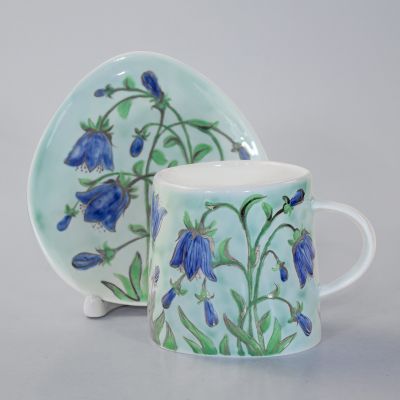 handmade caeramic cup and a saucer with bells