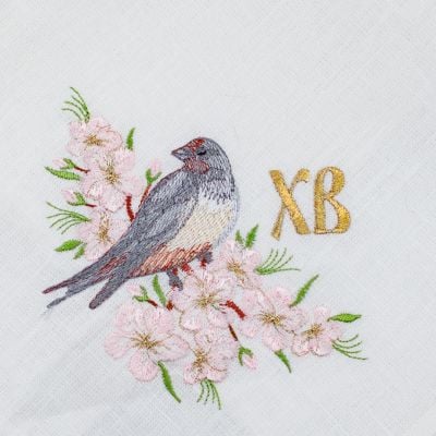 paschal red linen kitchen napkin with embroidered birds and cherry tree in blossom