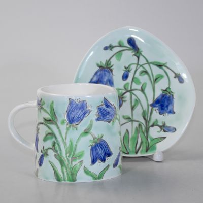 handmade caeramic cup and a saucer with bells