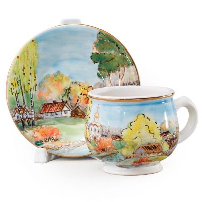 coffee cup and a saucer with sunny autumn scenery in the woods with a church